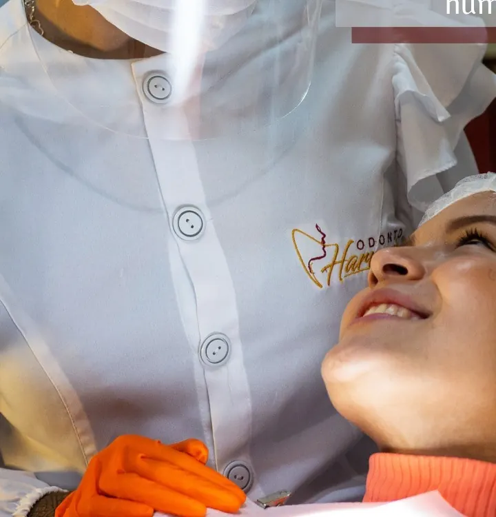 Profissional com protetor facial atendendo uma paciente na cadeira