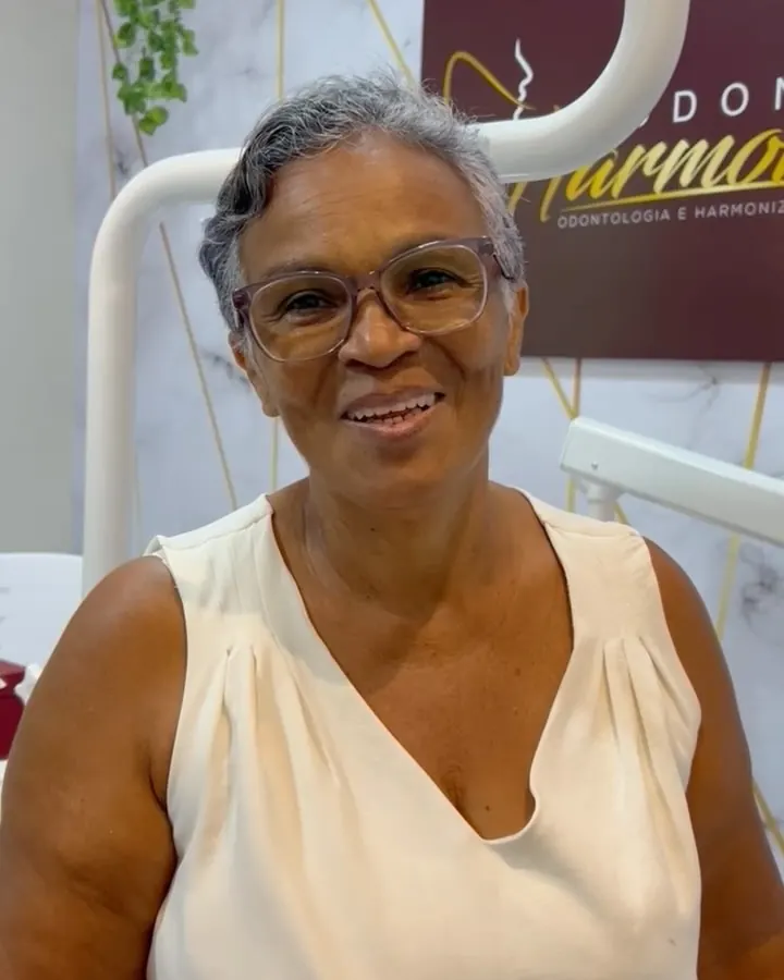 Paciente sorrindo na cadeira depois de receber a prótese nova
